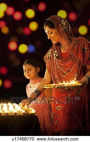 Mother placing diyas on a table while her daughter looks on View Large Photo Image Stock Image - Mother placing diyas on a table while her daughter looks on . Fotosearch