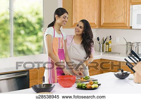 Stock Photography - Mother teaching her daughter to cut vegetables . Fotosearch