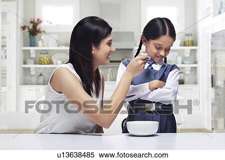 Mother trying to feed daughter breakfast View Large Photo Image Stock Photography - Mother trying to feed daughter breakfast . Fotosearch