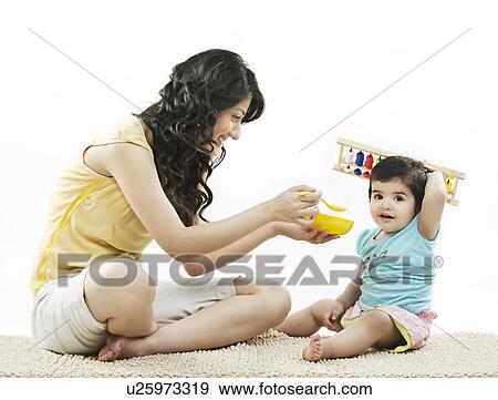 Mother trying to feed her child  View Large Photo Image Stock Photo - Mother trying to feed her child . Fotosearch