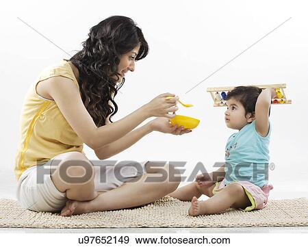Stock Photo - Mother trying to feed her child . Fotosearch