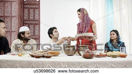 Stock Photograph - Muslim woman serving food during Id . Fotosearch