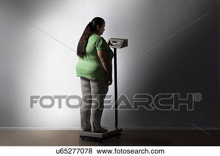 Obese woman checking her weight View Large Photo Image Stock Photo - Obese woman checking her weight . Fotosearch