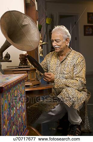 Old man looking at a record View Large Photo Image Stock Photo - Old man looking at a record . Fotosearch