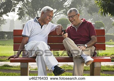 Stock Image - Old men reading an sms . Fotosearch