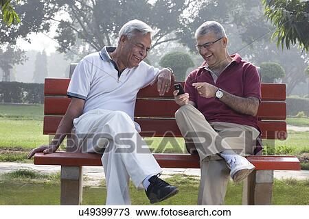 Stock Image - Old men reading an sms . Fotosearch