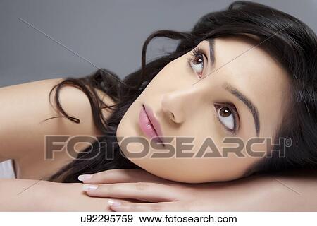 Pensive young woman looking up over colored background View Large Photo Image Stock Photo - Pensive young woman looking up over colored background . Fotosearch