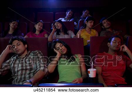 Picture - People sleeping inside a cinema hall . Fotosearch