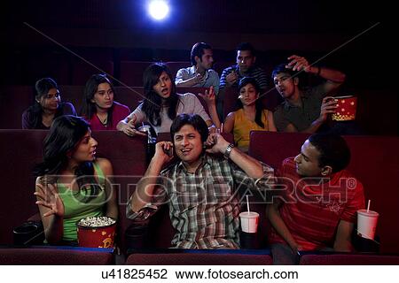Stock Image - People staring at a man inside a cinema hall . Fotosearch