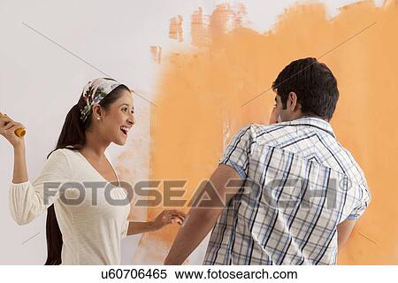Playful young couple having fun together while painting their house View Large Photo Image Stock Photography - Playful young couple having fun together while painting their house . Fotosearch