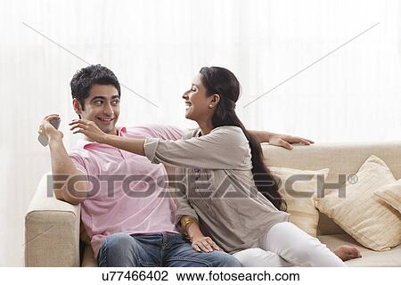 Playful young man keeping remote control away from woman View Large Photo Image Stock Image - Playful young man keeping remote control away from woman . Fotosearch