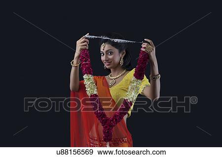 Stock Photo - Portrait of a beautiful bride holding a garland. Fotosearch