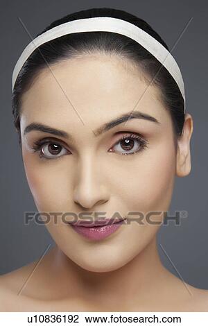 Stock Image - Portrait of a beautiful young woman smiling over colored background . Fotosearch