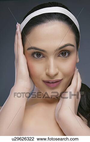 Portrait of a beautiful young woman touching her face over colored background View Large Photo Image Stock Image - Portrait of a beautiful young woman touching her face over colored background . Fotosearch