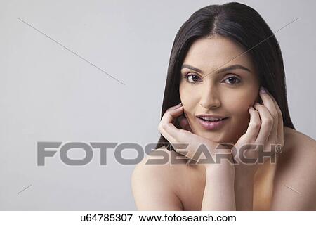 Portrait of a beautiful young woman touching her face over colored background View Large Photo Image Stock Photo - Portrait of a beautiful young woman touching her face over colored background . Fotosearch