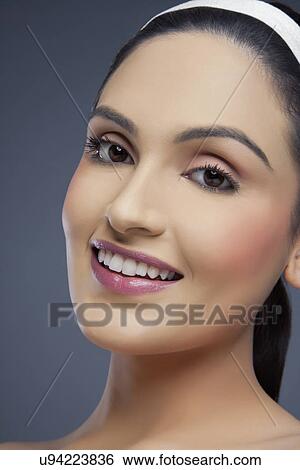Stock Photograph - Portrait of a beautiful young woman smiling over colored background . Fotosearch