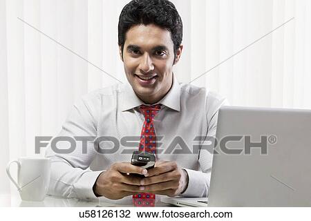 Stock Image - Portrait of a businessman holding a mobile phone . Fotosearch