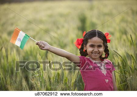 Stock Image - Portrait of a cheerful little girl holding an Indian flag . Fotosearch