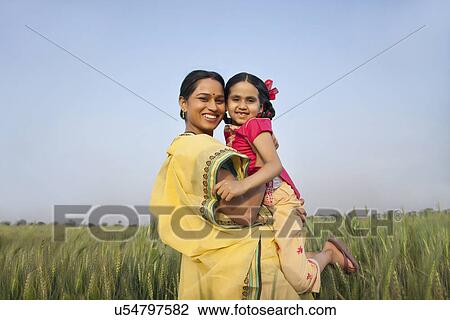 Portrait of a cheerful mother carrying daughter against clear sky in a wheat field View Large Photo Image Stock Image - Portrait of a cheerful mother carrying daughter against clear sky in a wheat field . Fotosearch
