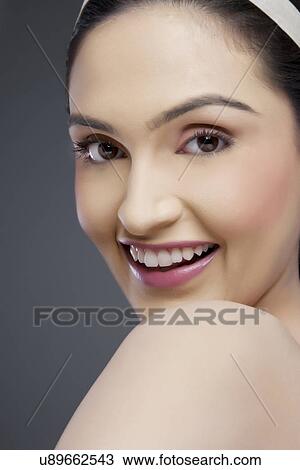 Stock Image - Portrait of a cheerful young woman over colored background . Fotosearch