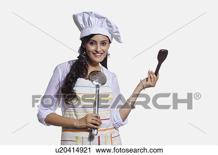 Stock Image - Portrait of a female chef with cooking utensils. Fotosearch