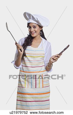 Stock Image - Portrait of a female chef with cooking utensils. Fotosearch