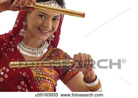 Stock Image - Portrait of a female dandiya dancer with sticks . Fotosearch