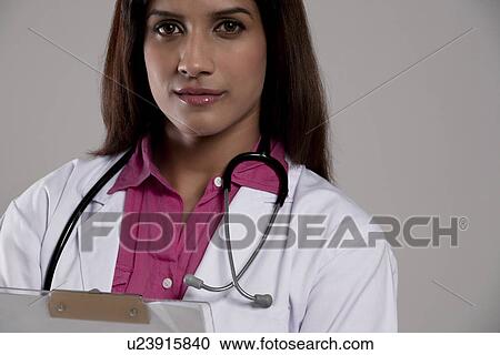 Stock Image - Portrait of a female doctor with a clip board . Fotosearch