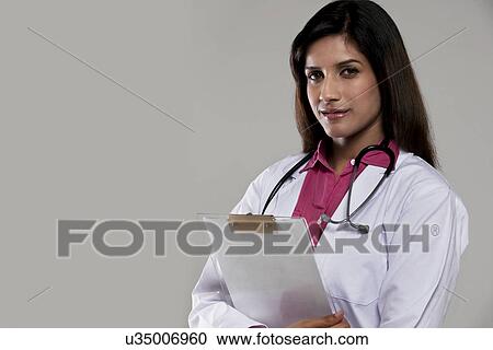 Stock Image - Portrait of a female doctor with a clip board . Fotosearch
