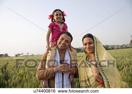 Portrait of a happy family in field with girl on father's shoulders View Large Photo Image Stock Photograph - Portrait of a happy family in field with girl on father's shoulders . Fotosearch