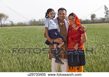 Portrait of a happy family of three standing together with field in background  View Large Photo Image Stock Photography - Portrait of a happy family of three standing together with field in background . Fotosearch