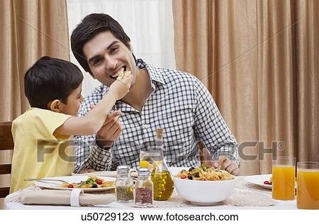 Portrait of a happy father being fed a piece of pizza by his son View Large Photo Image Stock Image - Portrait of a happy father being fed a piece of pizza by his son . Fotosearch