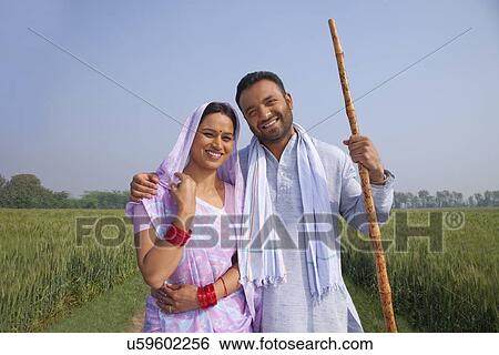 Stock Photograph - Portrait of a happy Indian couple standing in a field . Fotosearch