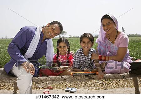 Portrait of a happy Indian family sitting on cot View Large Photo Image Stock Image - Portrait of a happy Indian family sitting on cot . Fotosearch