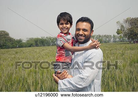 Portrait of a happy man carrying his son with wheat field in background View Large Photo Image Stock Image - Portrait of a happy man carrying his son with wheat field in background . Fotosearch