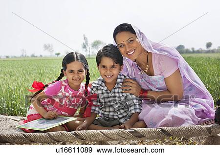 Portrait of a happy mother sitting with her children on cot View Large Photo Image Stock Photo - Portrait of a happy mother sitting with her children on cot . Fotosearch