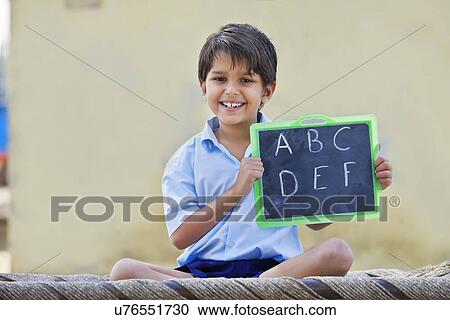 Portrait of a happy school boy holding slate with English alphabet on it View Large Photo Image Stock Image - Portrait of a happy school boy holding slate with English alphabet on it . Fotosearch