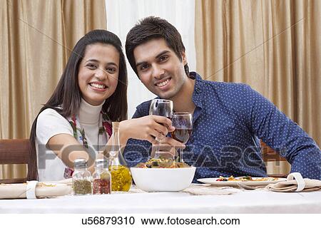 Stock Image - Portrait of a happy young couple having wine at restaurant . Fotosearch