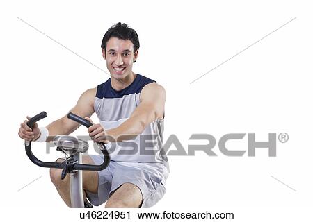 Portrait of a happy young man on exercise bike over white background View Large Photo Image Stock Image - Portrait of a happy young man on exercise bike over white background . Fotosearch