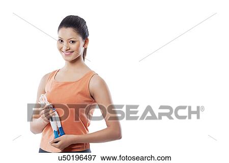 Stock Photo - Portrait of a happy young woman holding jump rope over white background . Fotosearch