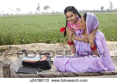 Portrait of a little girl embracing her mother with field in background View Large Photo Image Stock Image - Portrait of a little girl embracing her mother with field in background . Fotosearch