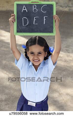 Portrait of a little girl in school uniform holding slate View Large Photo Image Stock Photo - Portrait of a little girl in school uniform holding slate . Fotosearch