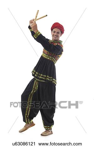 Stock Image - Portrait of a male dandiya dancer with sticks . Fotosearch