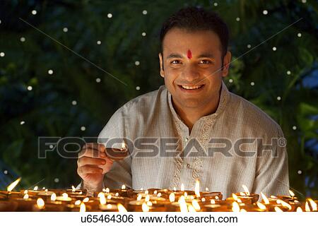 Stock Photograph - Portrait of a man holding a diya . Fotosearch