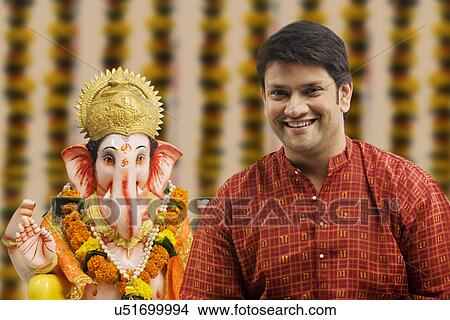 Picture - Portrait of a man with a Ganesh idol . Fotosearch