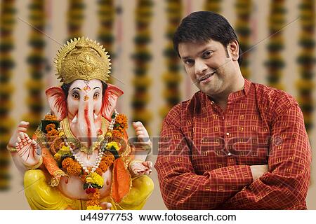 Stock Image - Portrait of a man with a Ganesh idol . Fotosearch