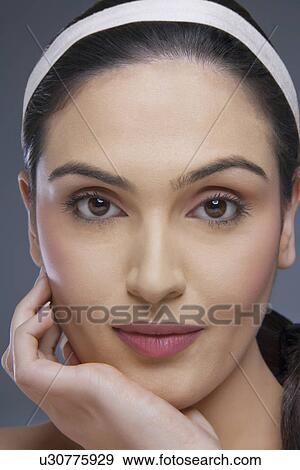 Portrait of a pretty female with hand on chin over colored background View Large Photo Image Stock Photo - Portrait of a pretty female with hand on chin over colored background . Fotosearch