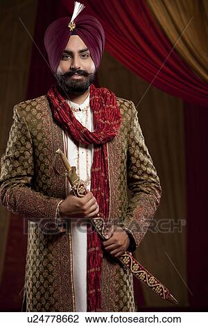 Stock Image - Portrait of a Sikh groom holding a sword . Fotosearch