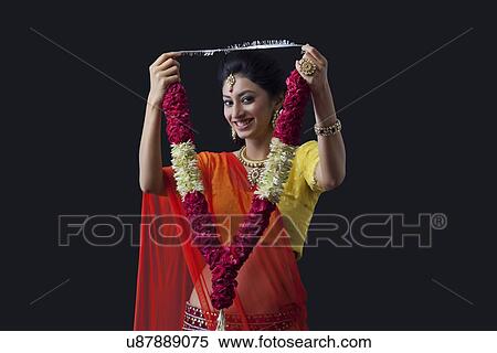 Stock Photography - Portrait of a smiling bride holding a garland. Fotosearch