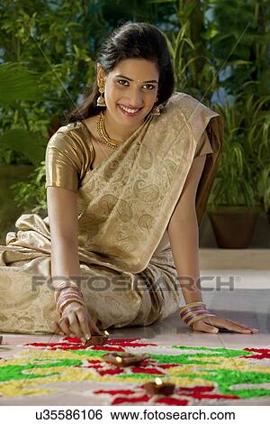 Stock Photograph - Portrait of a woman arranging diyas . Fotosearch